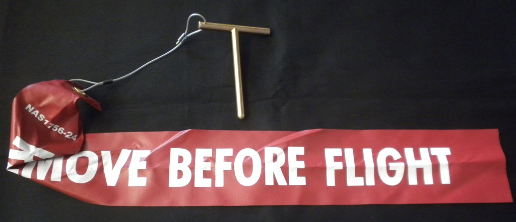 Safety-red remove-before-flight streamer and pin assembly used for aircraft maintenance while on ground